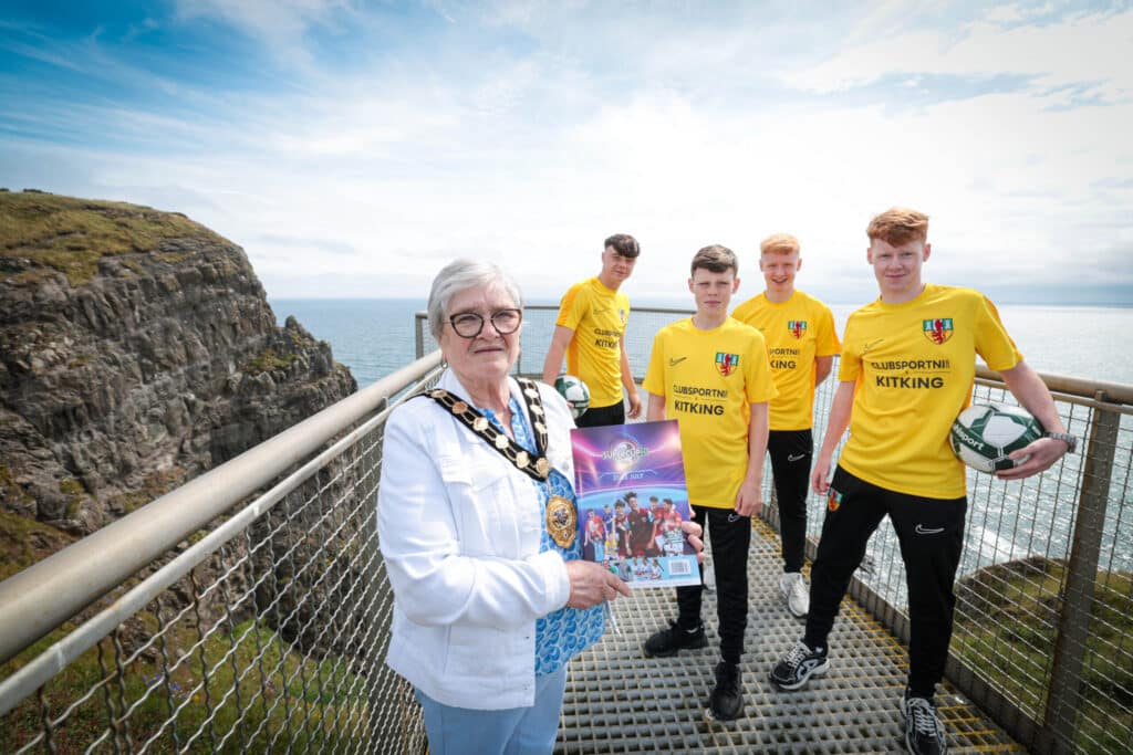 Mid and East Antrim Borough Council is wishing local and international teams competing at the 2024 SuperCupNI the best of luck as it gets set to host some of the world’s most talented young footballers as part of this year’s tournament. The 2024 SuperCupNI, celebrating its 41st year, will kick off with its traditional welcome parade and opening ceremony in Coleraine on Sunday 21st July before an action-packed week of football gets underway on Monday 22nd July. The thrilling action will end with Finals Day on Friday 26th July.
Mayor of Mid & East Antrim Borough, Alderman Beth Adger MBE is pictured visiting the Borough’s Gobbins Coastal Cliff Path to meet Co. Antrim SuperCupNI Premier and Junior Squad members Jayden Charnley, Oisin Morgan, Finlay Millar and Cohen Beattie in the build-up to the tournament’s kick-off.