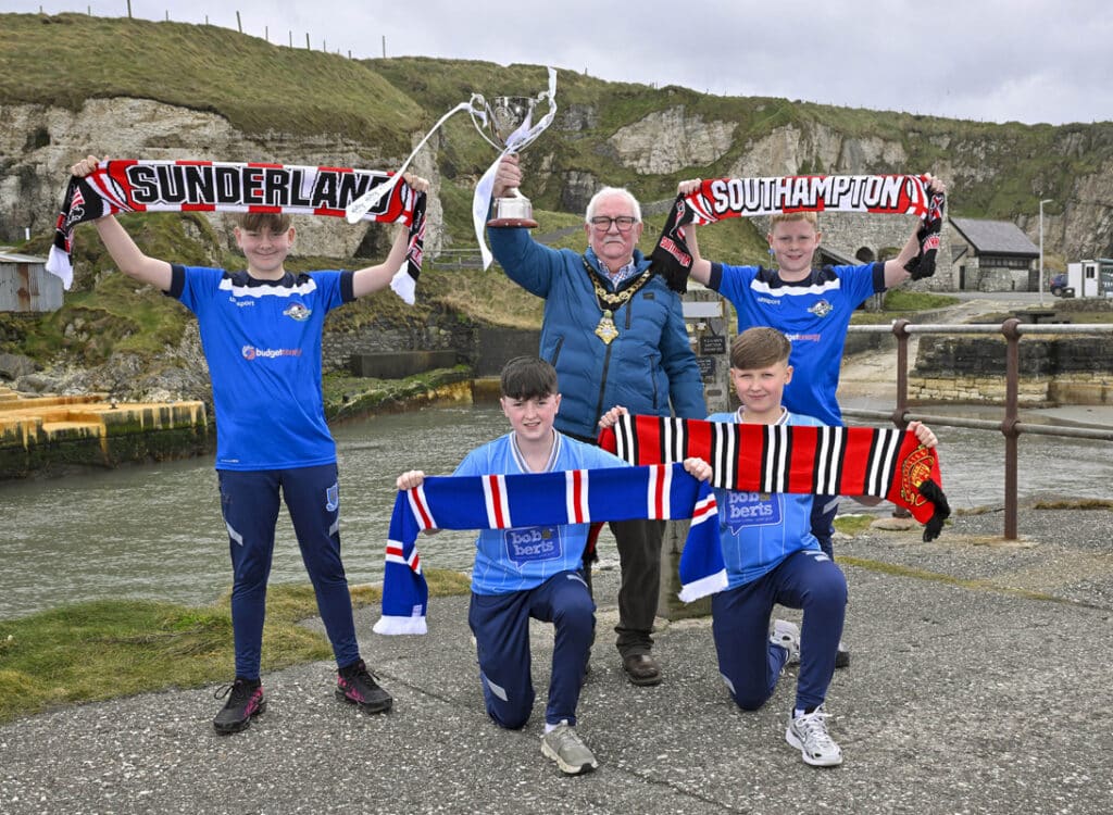 Ballymena United 2013s players Cole Logan, Curtis McKeown, Mason Buxton and William Shannon are pictured at Ballintoy Harbour alongside Mayor of Causeway Coast and Glens, Councillor Oliver McMullan, as the Budget Energy SuperCupNI confirms its 2026 Boys’ Premier Section line-up, featuring global heavyweights Manchester United and Sunderland, alongside Scottish giants Rangers and reigning champions Southampton.