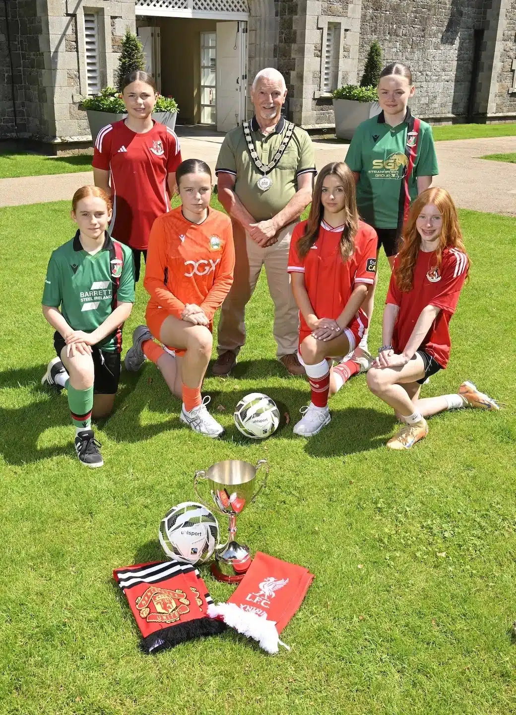 Councillor Henry Cushinan, Mayor of Antrim and Newtownabbey, and William Campbell, Director of the Budget Energy SuperCupNI, are pictured at the picturesque Clotworthy House in Antrim Castle Gardens with Crusaders players Kelly Robinson and Lily Steen, Glentoran players Eloise McAuley and Riah Totten, Amelia Fleming (Linfield) and Ria Conere (Cliftonville) ahead of the 2026 Budget Energy SuperCupNI Girls' Tournament.